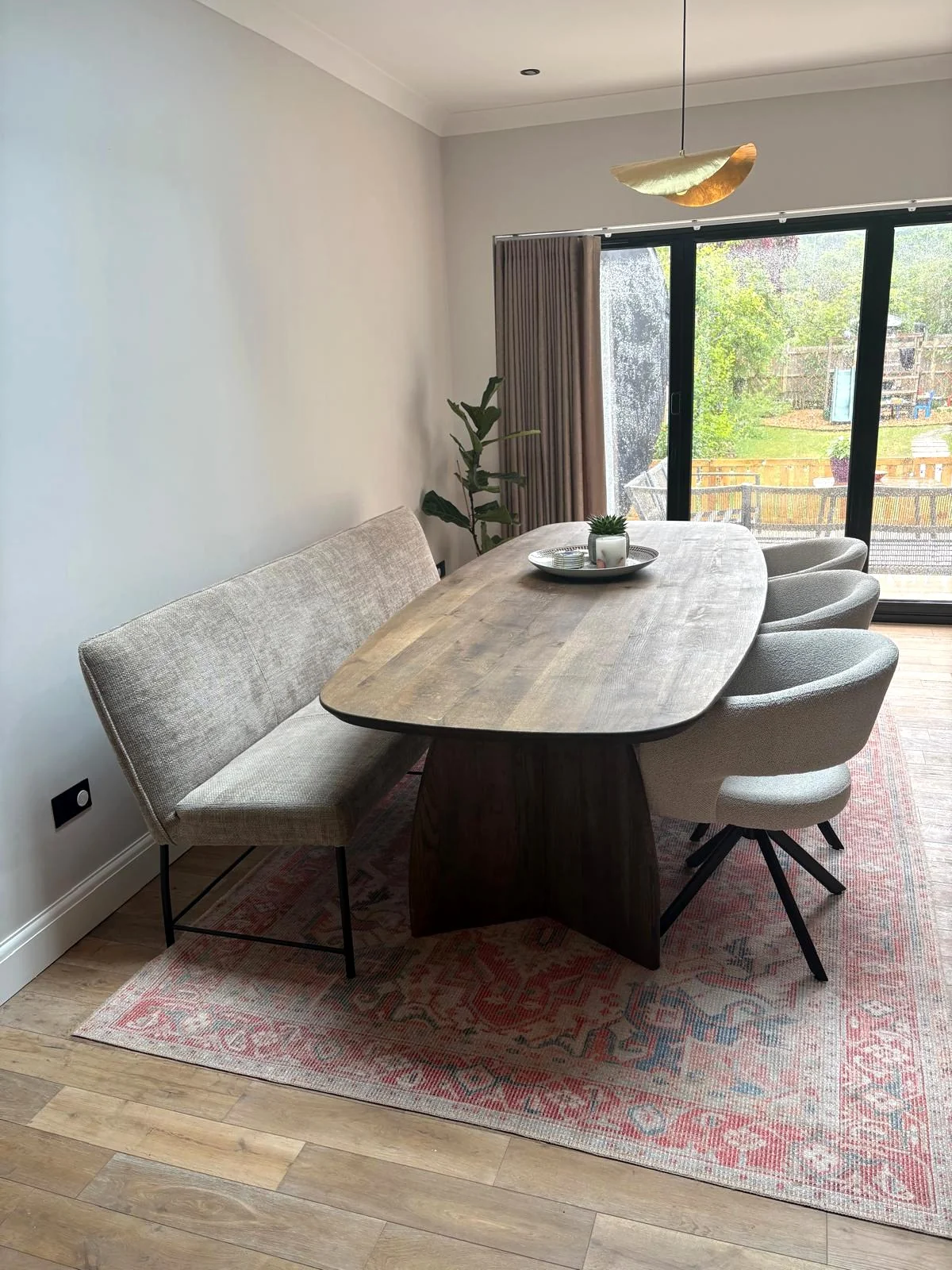 Forma solid oak oval dining table in a London home, with bench and bouclé chairs